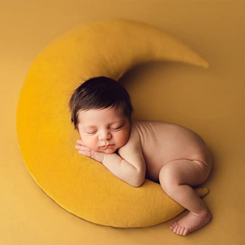 1. A newborn peacefully sleeping on a yellow pillow with a crescent shape.