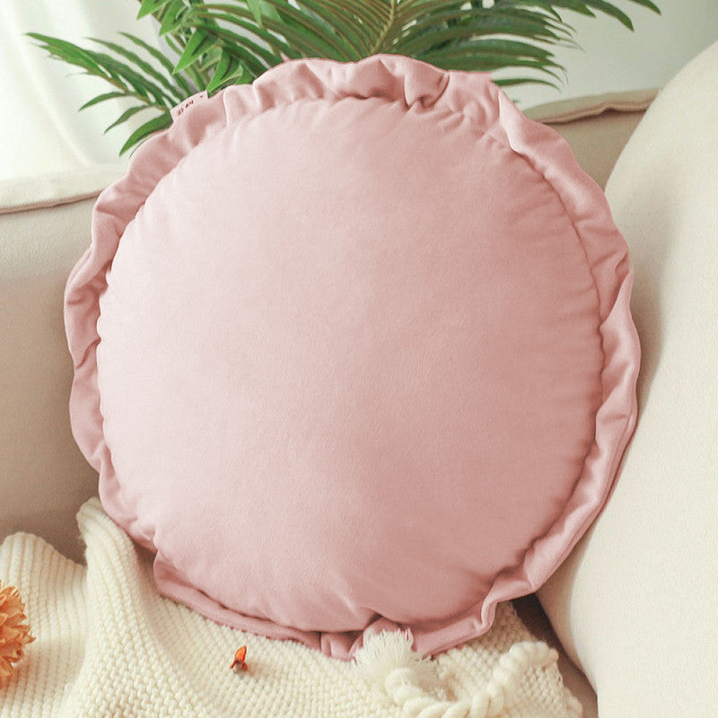 A round pillow adorned with  pink ruffles, adding a touch of elegance and charm to any space.