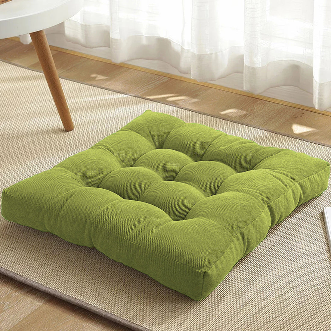 A green square cushion on a rug.