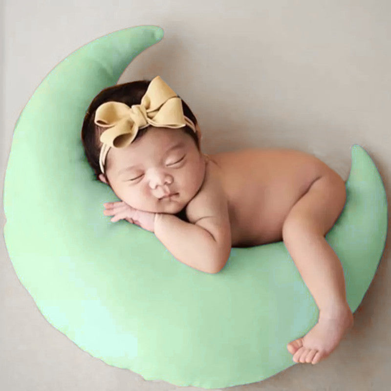 A peaceful baby girl sleeping on a green crescent pillow, dreaming sweet dreams.