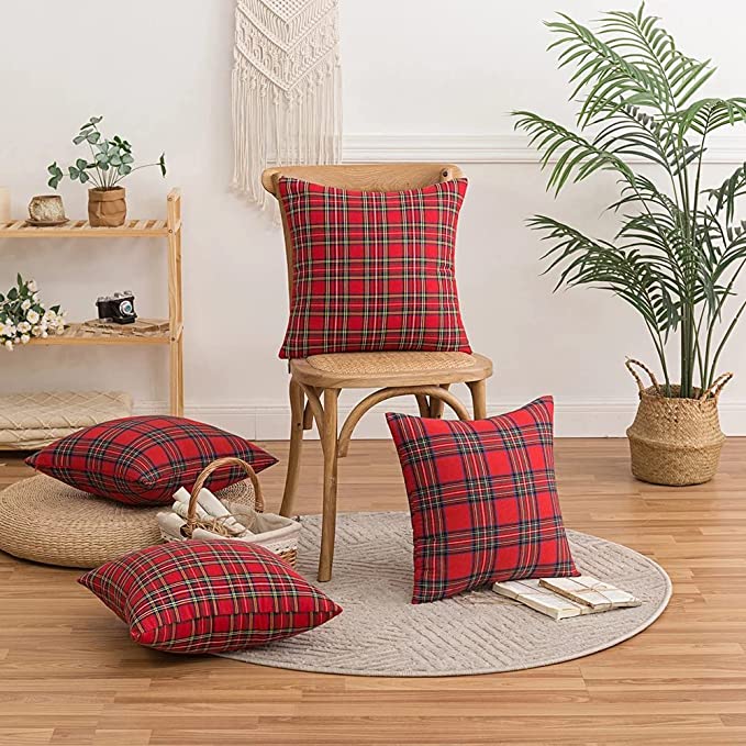 Red and black plaid pillow on chair with plant.