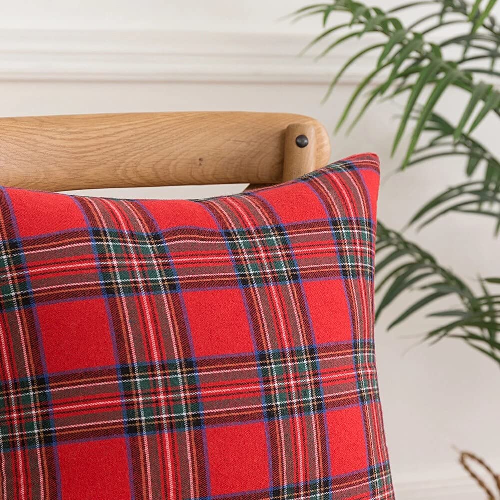 Chair with plant and red/black plaid pillow.