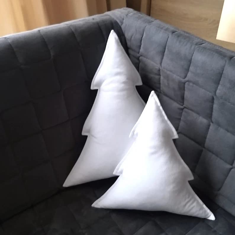 1. Two white pillows with Christmas trees embroidered on them. 2. Festive white pillows featuring Christmas tree designs. 3. White pillows adorned with cute Christmas tree patterns.