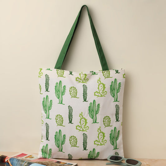 Green and white tote bag with cute cactus print, perfect for carrying essentials on a sunny day out.