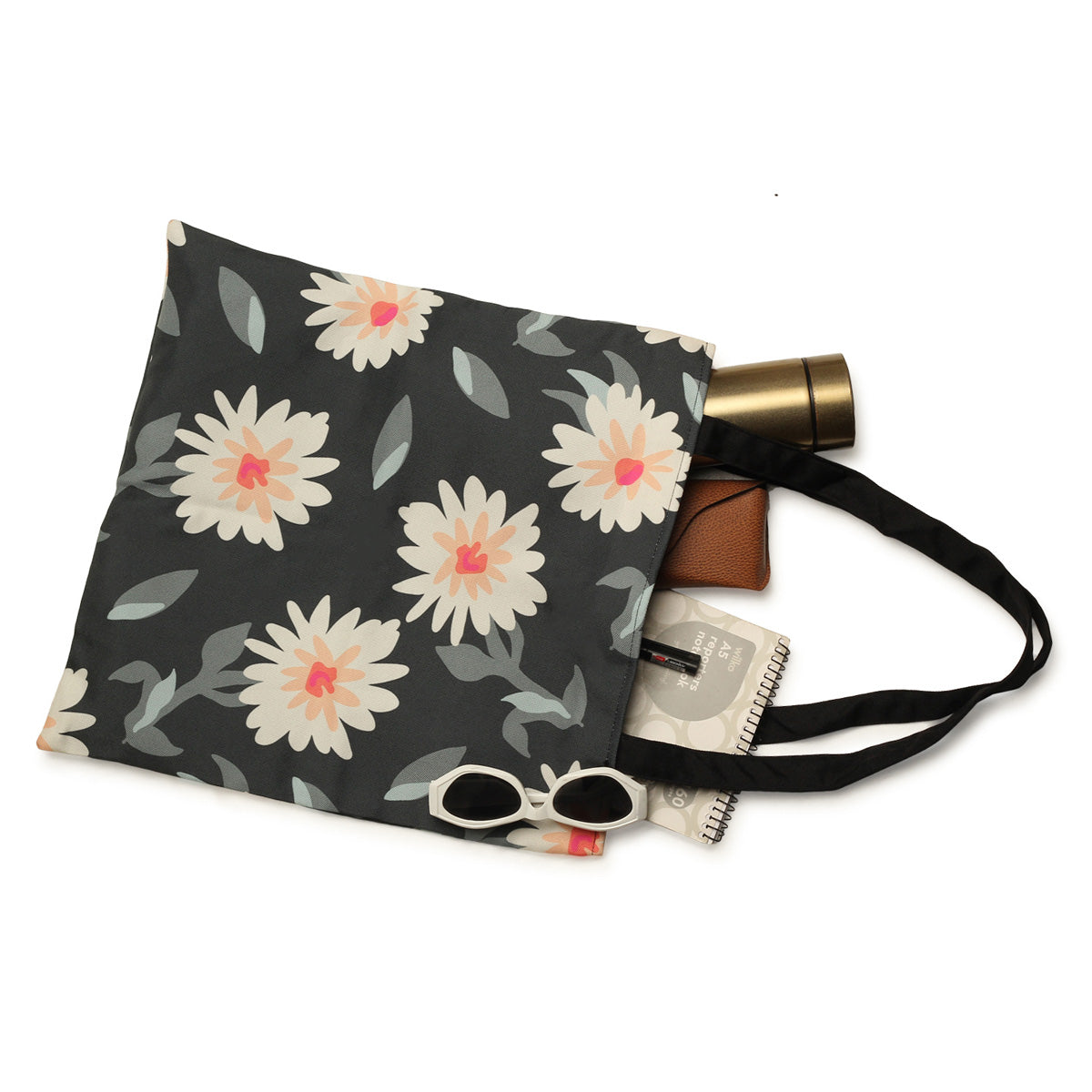 A floral patterned tote bag with a pair of sunglasses, a water bottle, a small brown wallet, and a notebook peeking out.