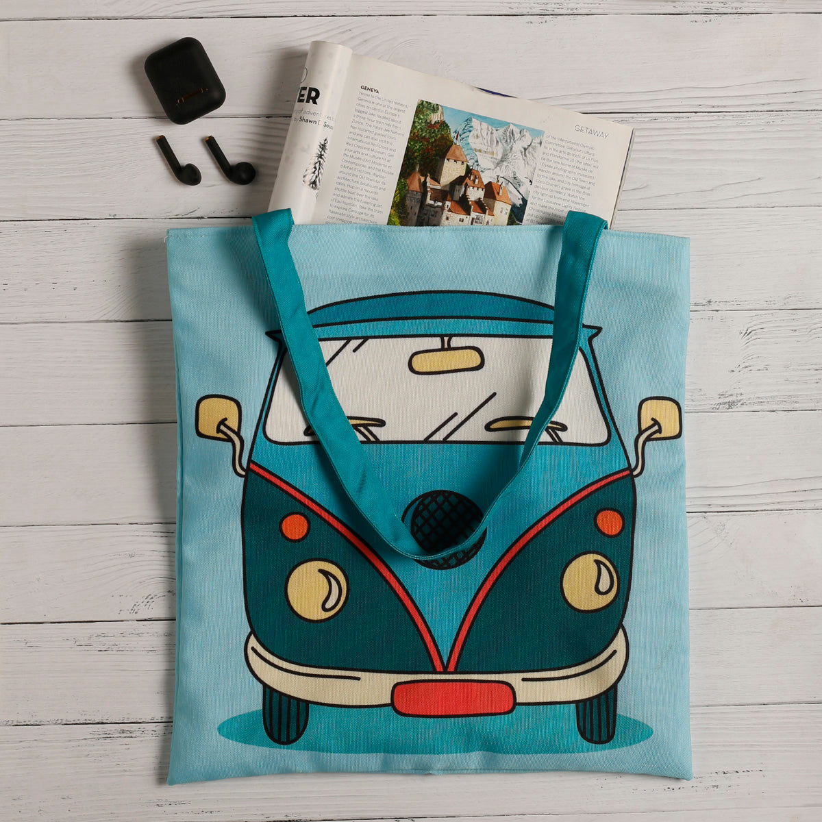 Blue Volkswagen bus tote bag with book and headphones.