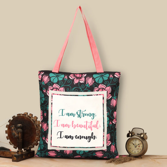 Black tote bag with a quote: ""I am strong, I am beautiful, I am strong"" surrounded by green and pick florals with pink color matching handle