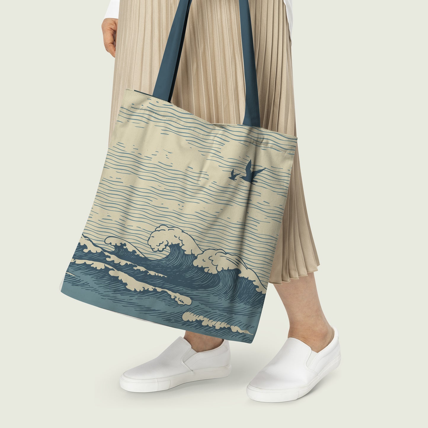 A Women holding a pleated beige skirt and white slip-on shoes carrying a tote bag with a blue and beige wave print design.