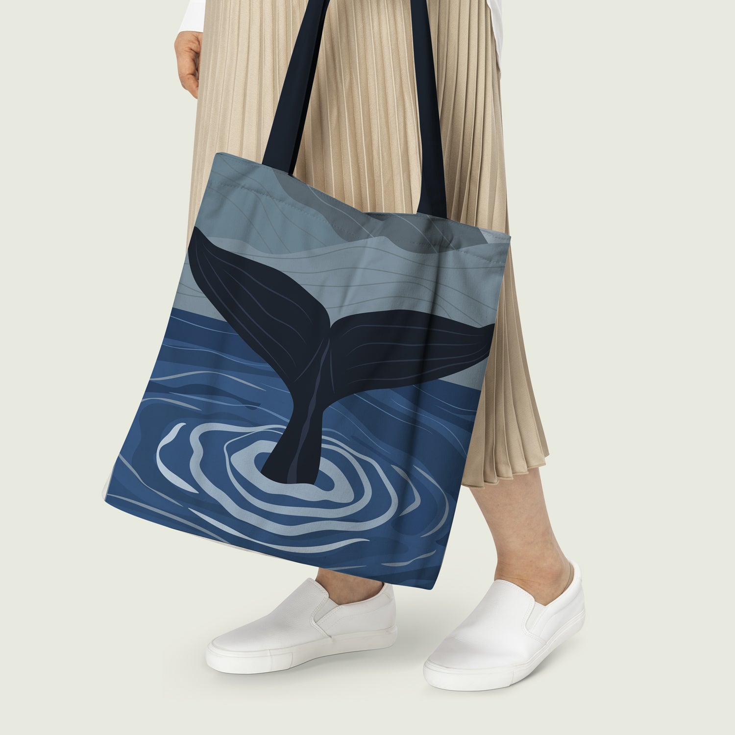 Stylish whale tail tote bag diving inside the ocean with blue sky above.