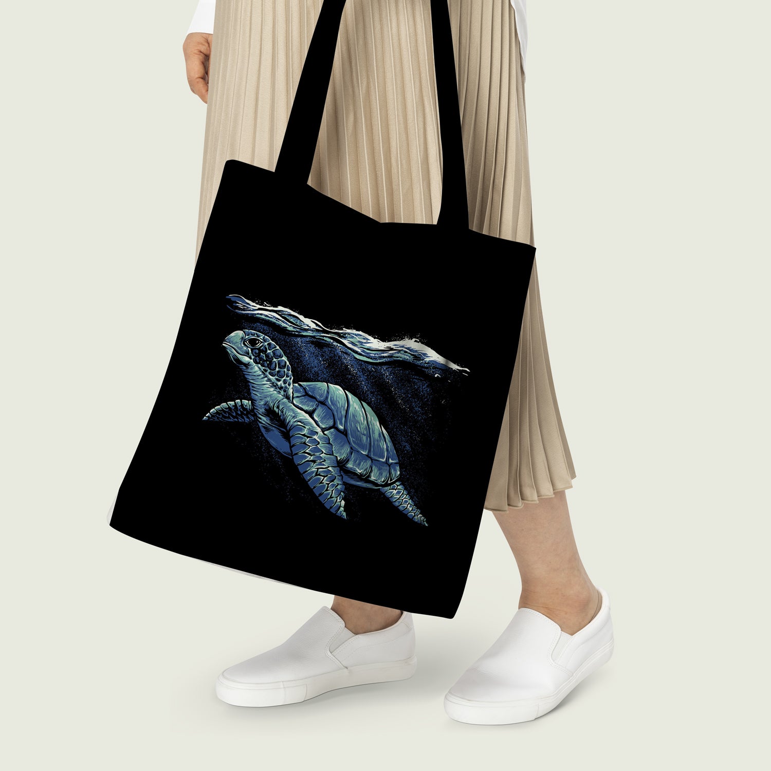 Stylish woman holding black tote bag featuring sea turtle design, adding a touch of nature to her outfit.