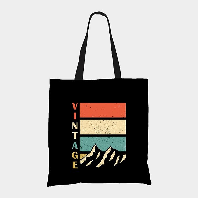 A stylish black tote bag featuring the phrase "vintage mountain" in a trendy font, perfect for everyday use.
