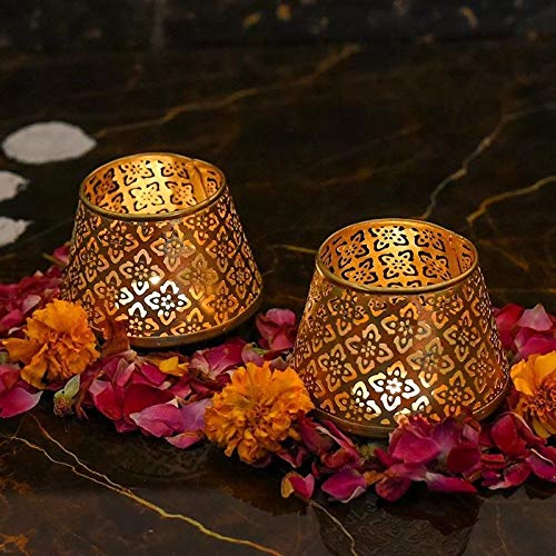 Two metallic gold tea lights on marble table.