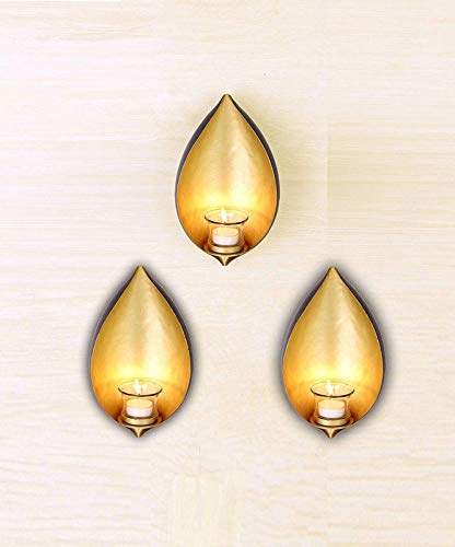 Three gold leaf shaped candles on a wooden surface