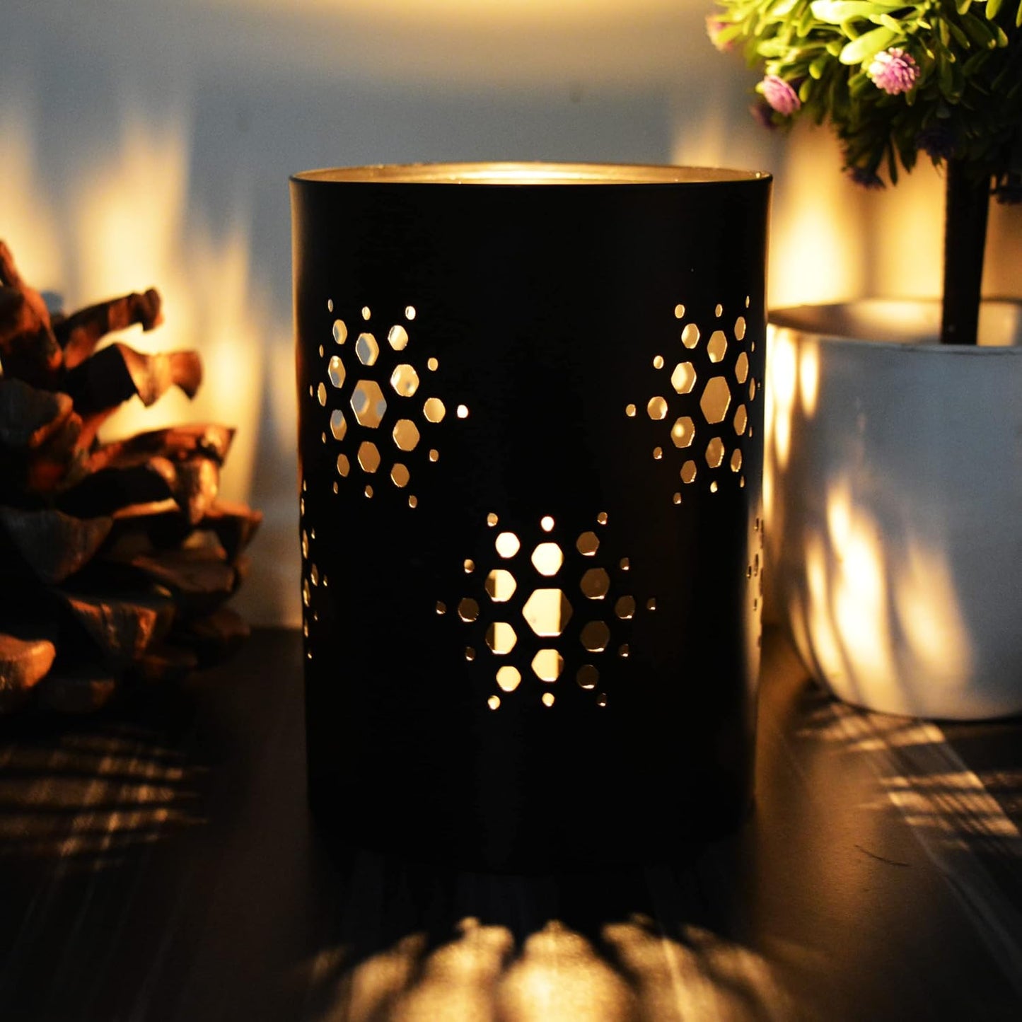 A black candle holder with decorative holes, perfect for adding a touch of elegance to any room.