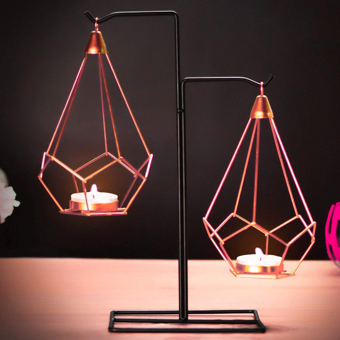 Two hanging candle holders with pink lights.