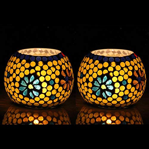 Two yellow glass tealights on black background.