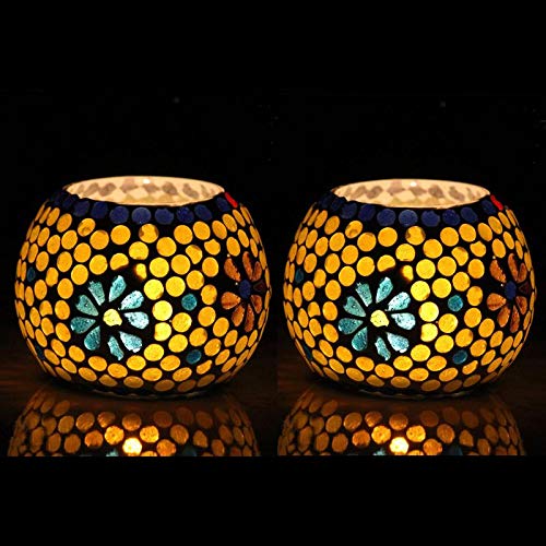 Two yellow glass tealights with black background.