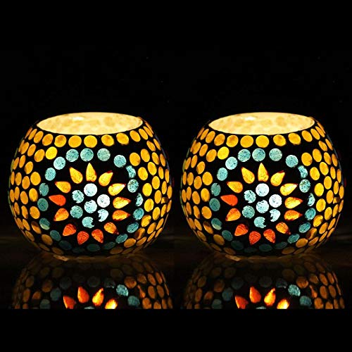 Two small glass tealights with colorful designs on a wooden background.