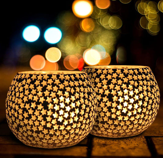 Two white and black tealights on a table, creating a cozy ambiance with their soft glow.