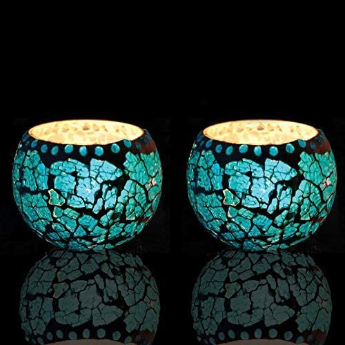 Pair of blue glass tea lights against dark backdrop.