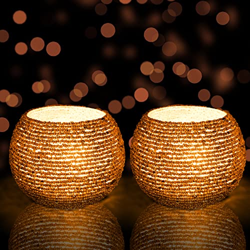  Pair of golden tea lights on dark backdrop.