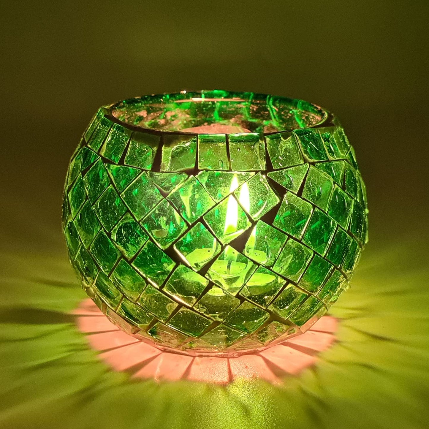 Glowing light inside a green glass candle holder.