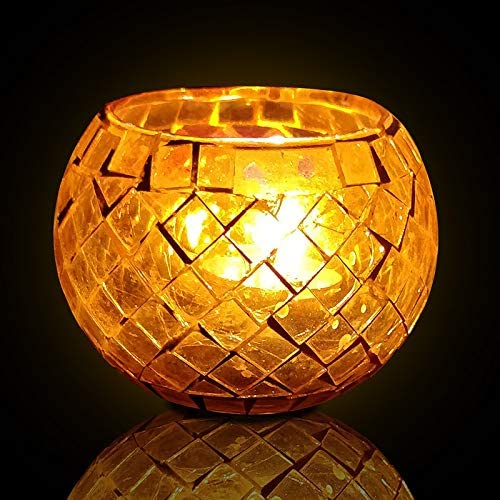  A golden glass candle holder glowing with light.