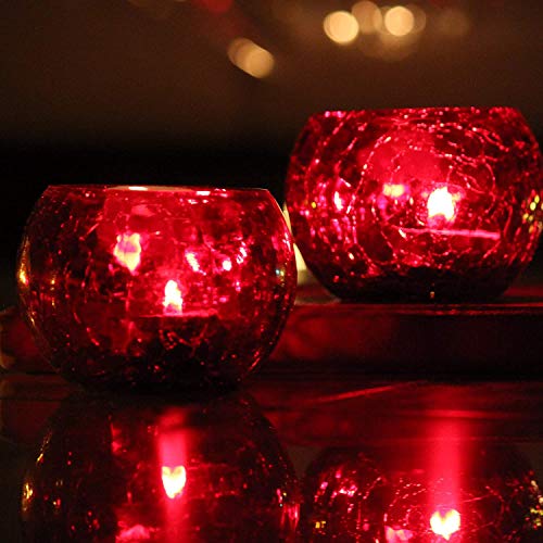 Two red glass tealights on a table.