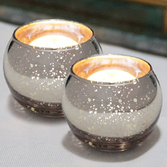 Glass tealight holders with candles glowing inside.