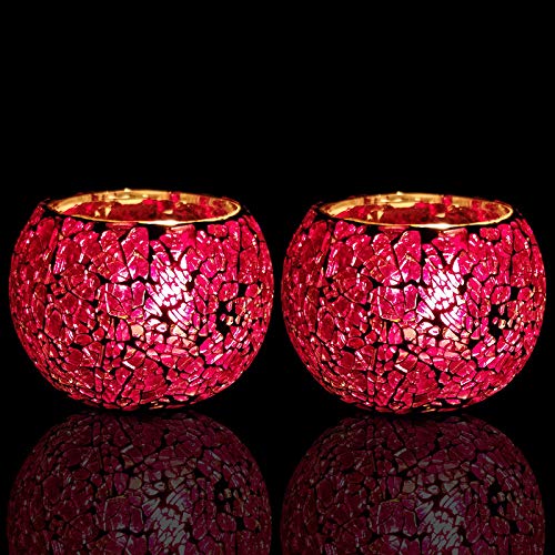 Two red glass tealights on a table.