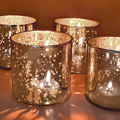 Four gold glass votives with white speckles arranged on a table.