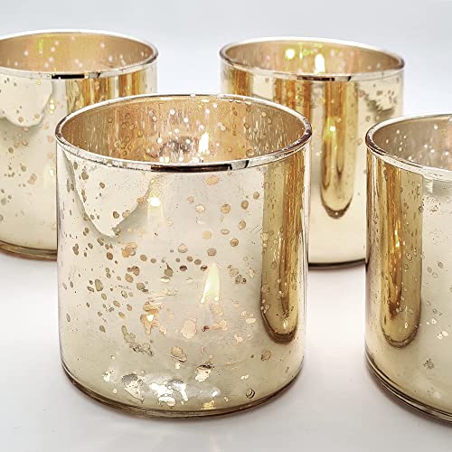 Four gold glass votives with white speckles arranged on a table.