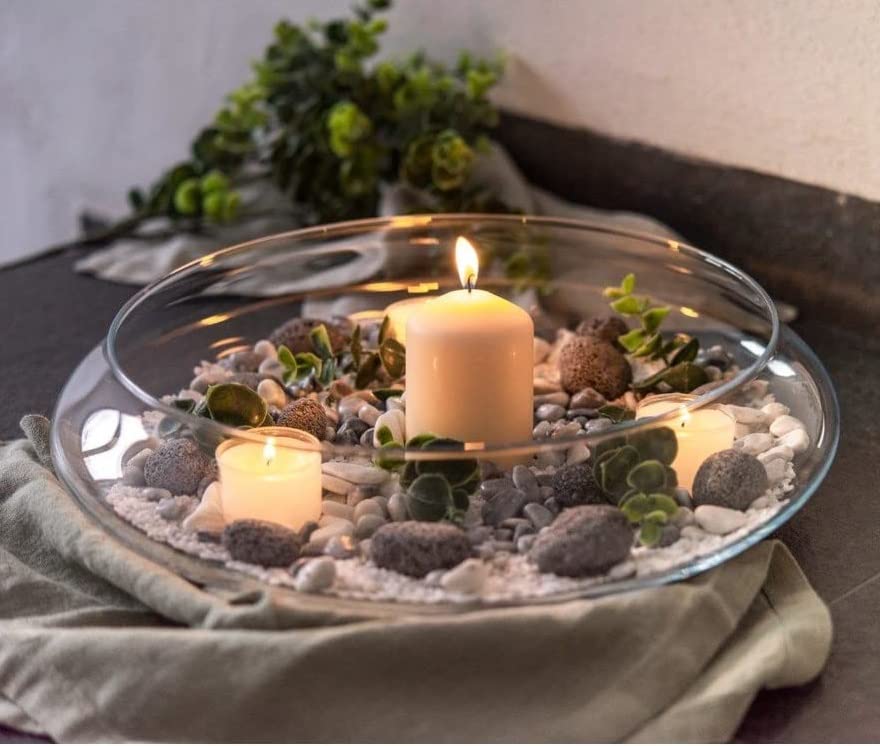 A candle in a glass bowl surrounded by rocks and stones.