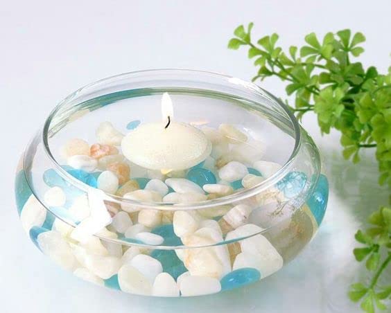 Glass bowl containing a candle with rocks and stones.