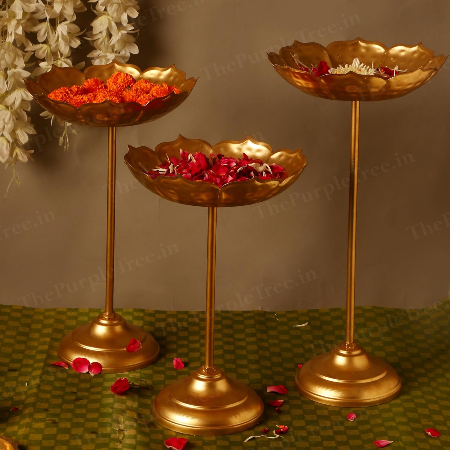 Three gold flower stands with colorful flowers on them.