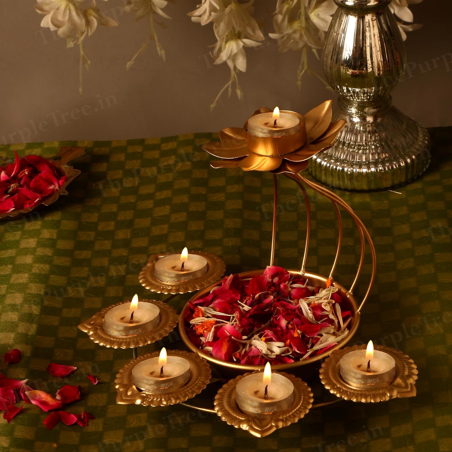 A gold candle holder with flowers and lit candles on a table