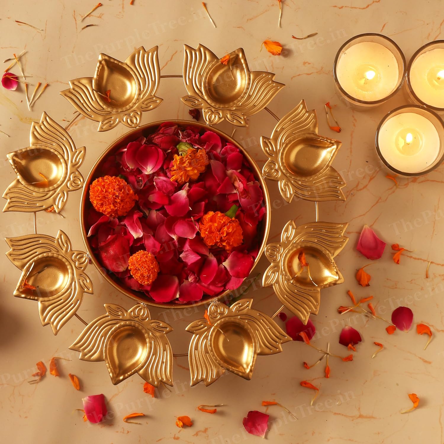 Elegant gold plated diya featuring flowers and candles for a special occasion.