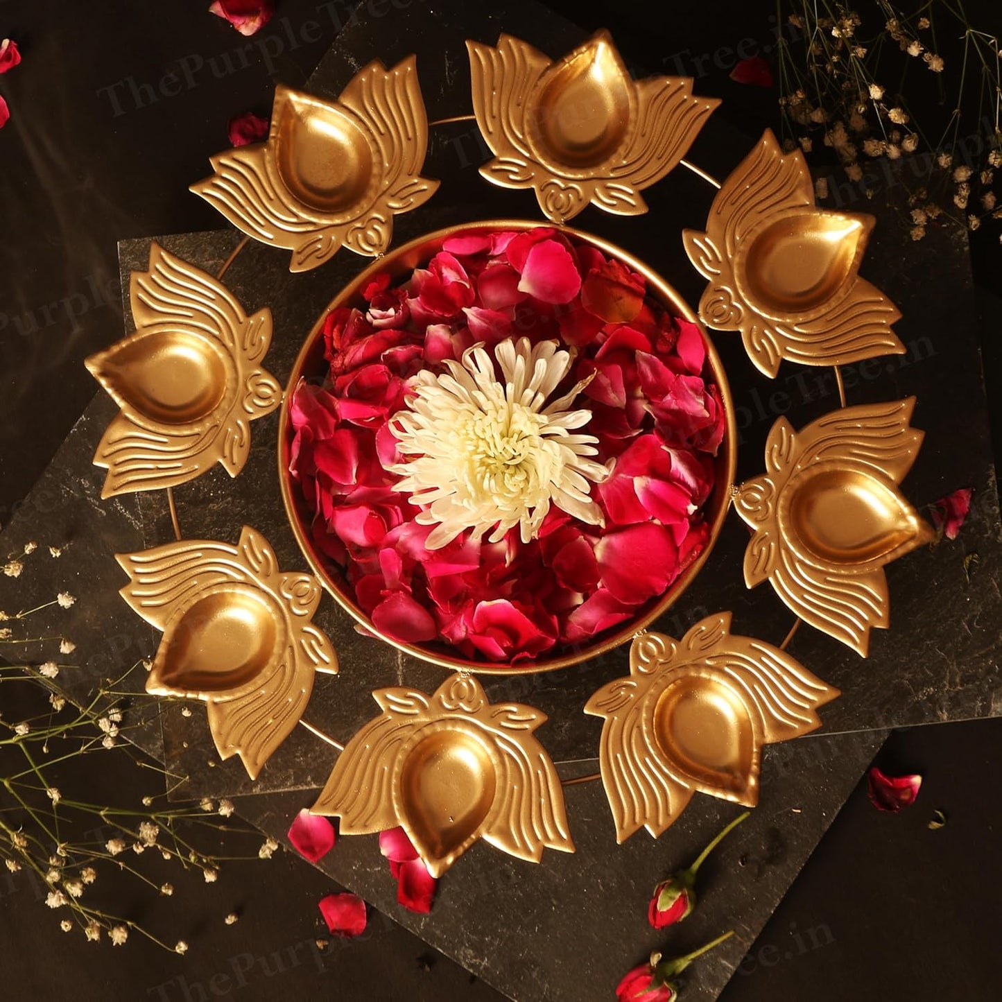 Gold plated diya adorned with flowers and candles for a festive ambiance.