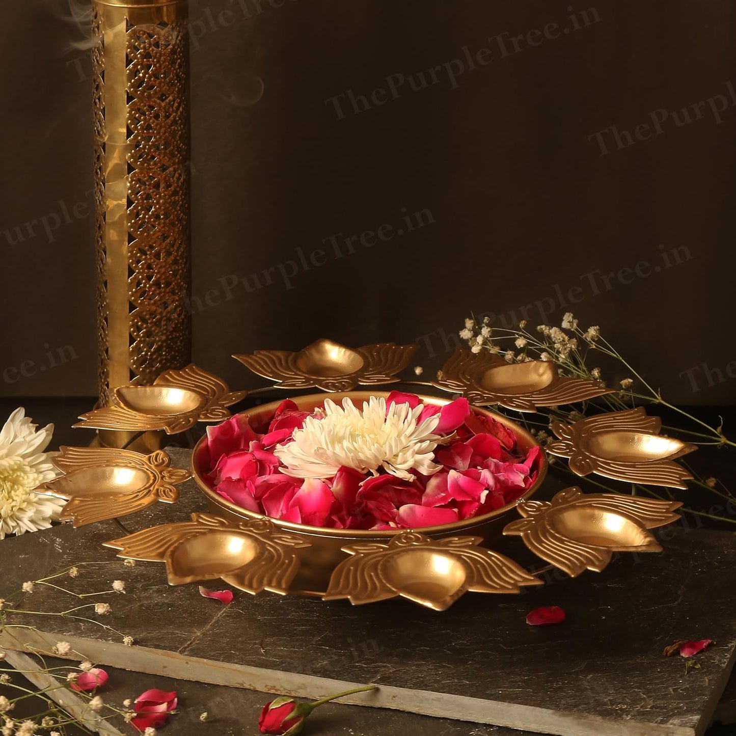 A beautiful gold plated diya adorned with flowers and candles, adding a touch of elegance and warmth to any occasion.