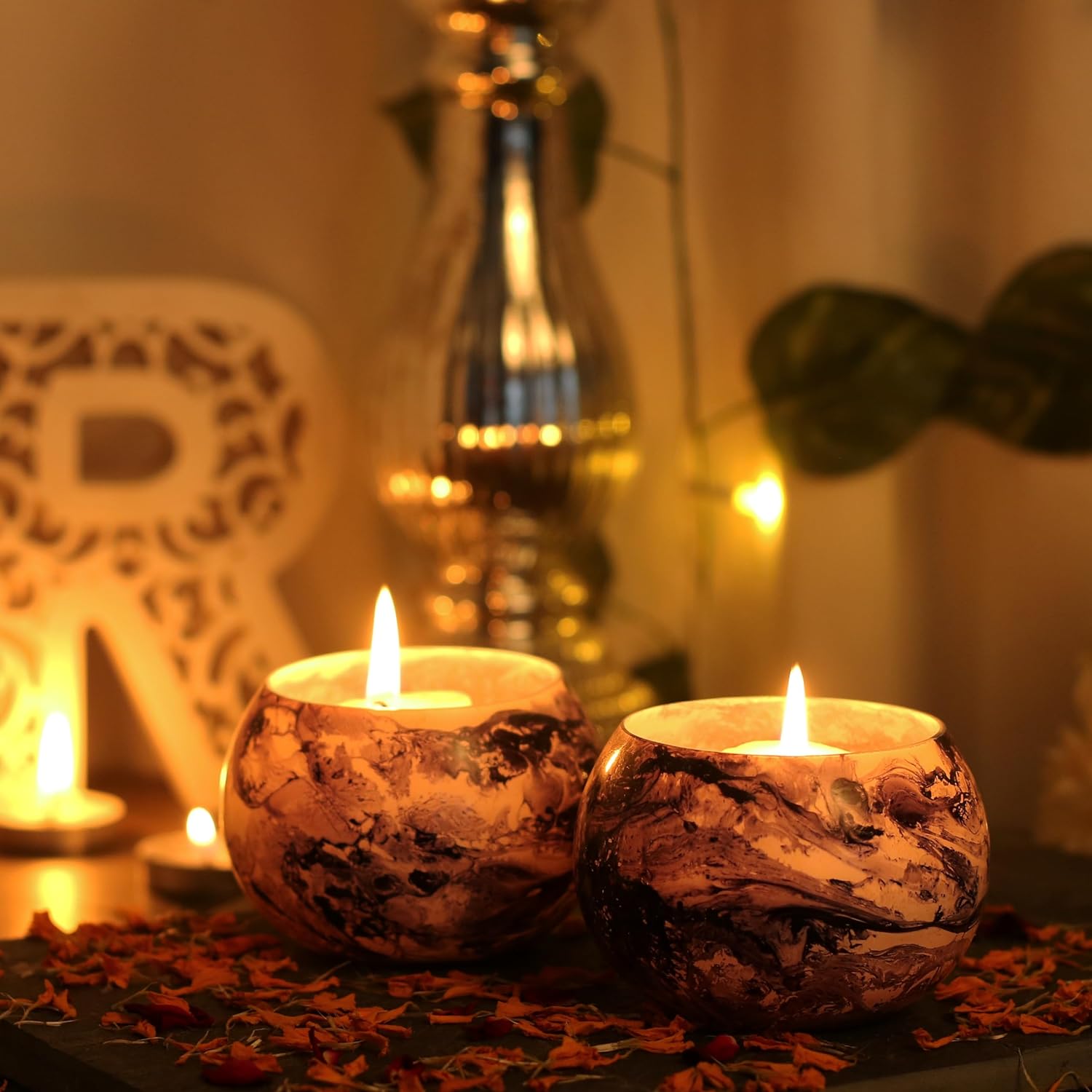 Two candles in silver candle holder on wooden table.