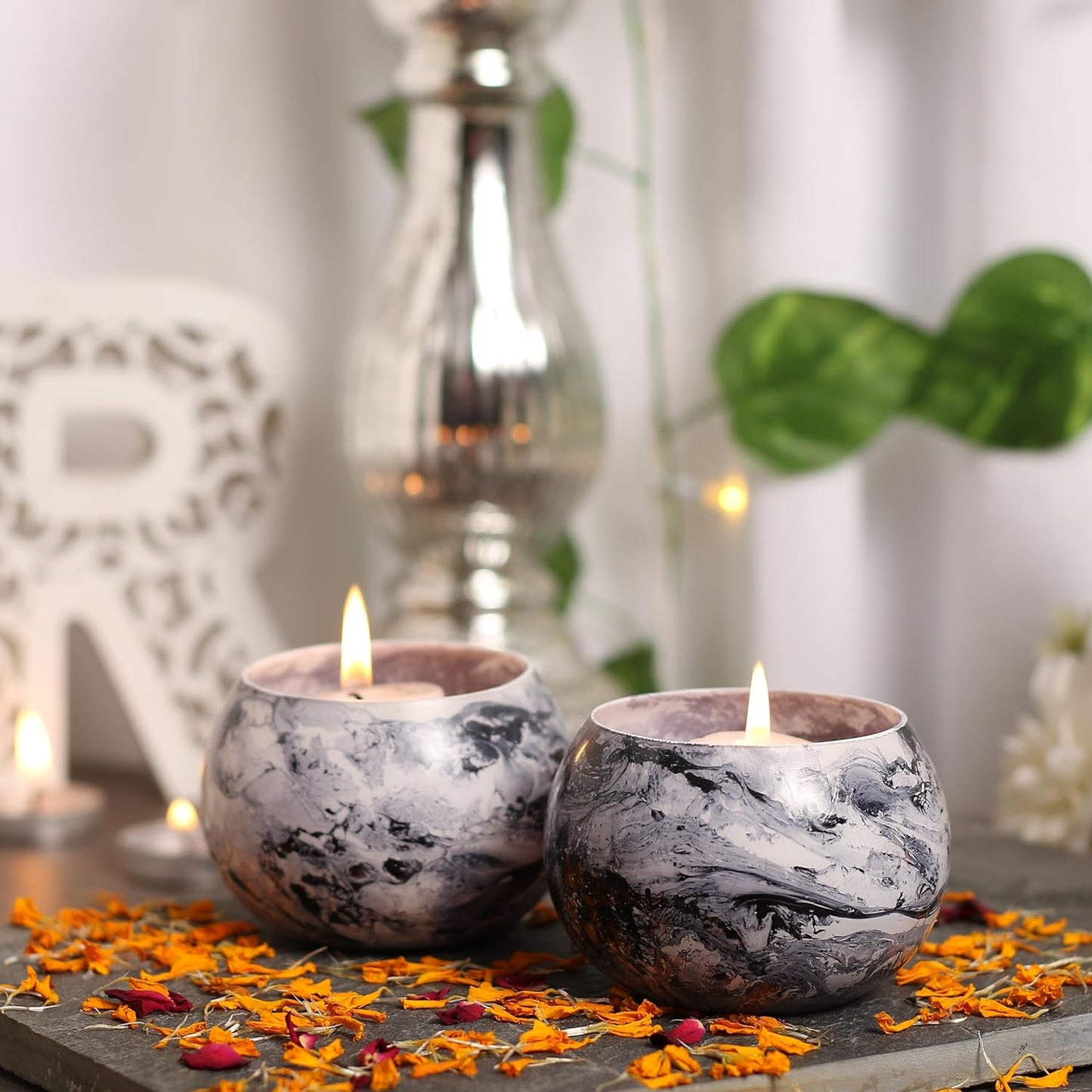 Two candles on table with flowers, creating a cozy atmosphere.