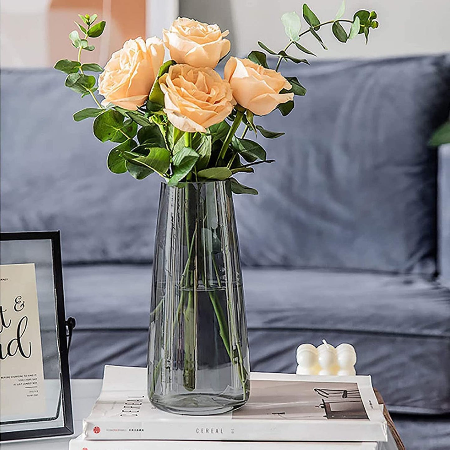 Flowers in a vase placed beside a book on a table.