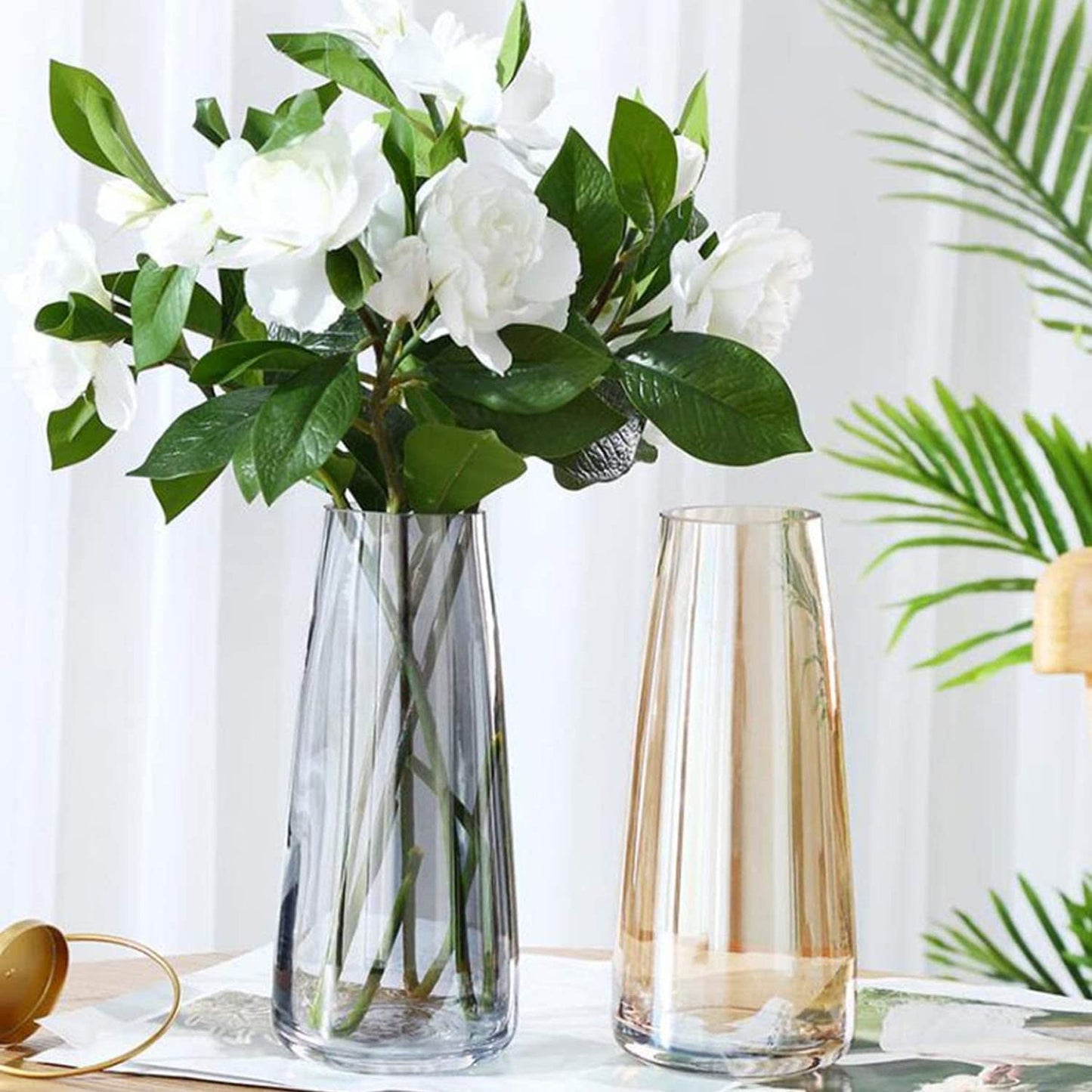  Two vases filled with white flowers on a wooden table.