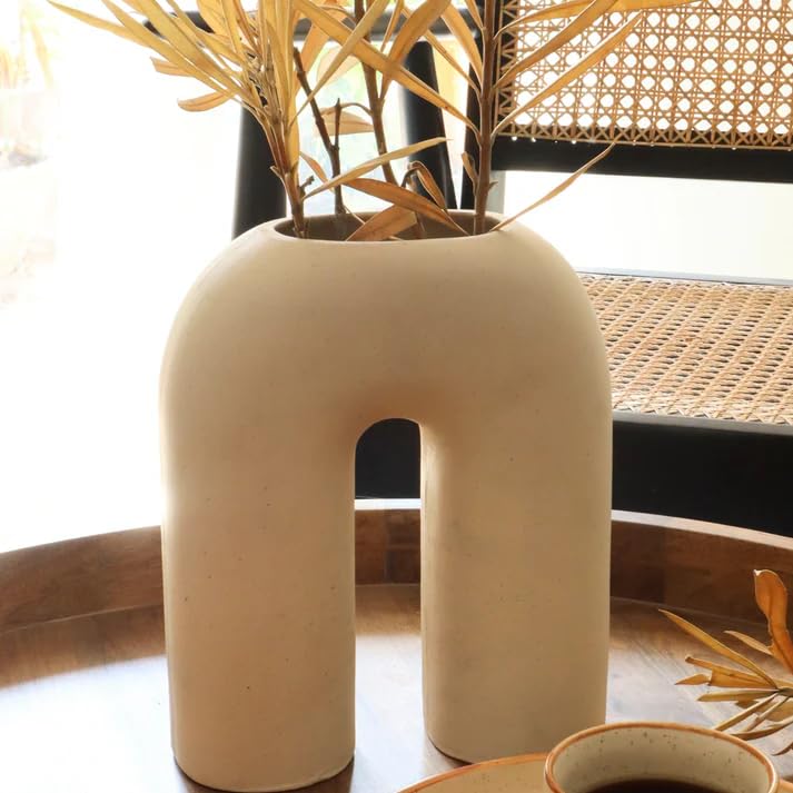 A white vase with a plant on a table, adding a touch of nature to the room's decor.