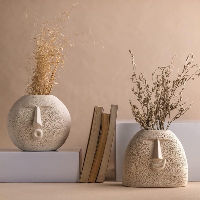 Two decorative vases with unique faces displayed on a table.