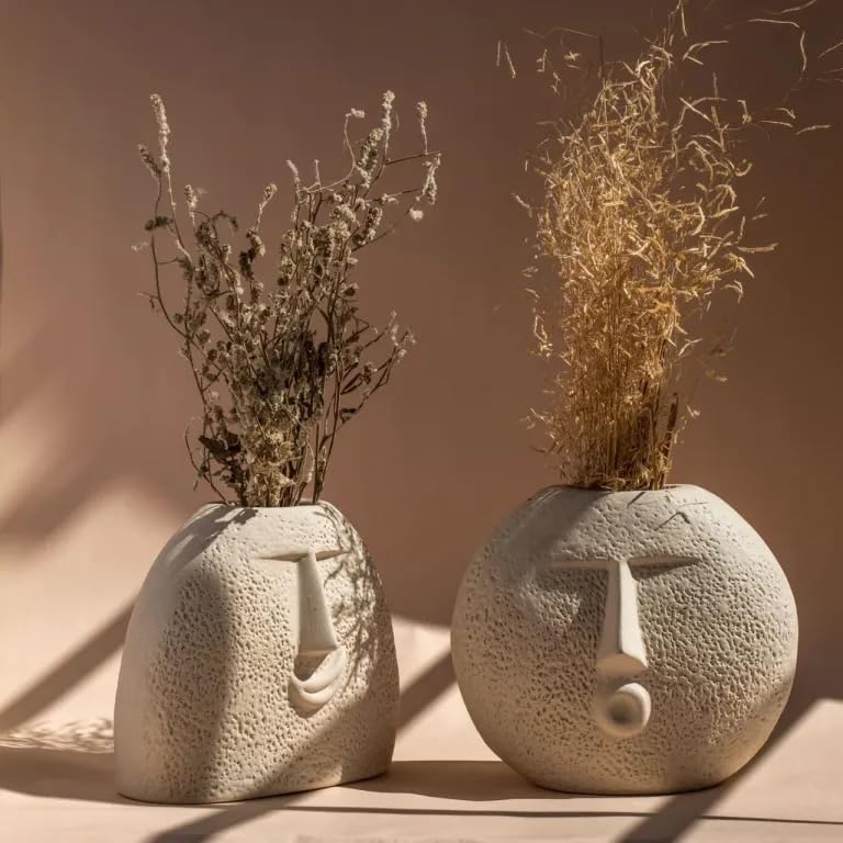 A pair of vases featuring facial designs placed on a table.