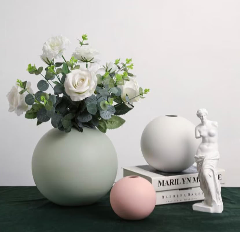 A beautiful vase filled with colorful flowers and a statue standing beside it.