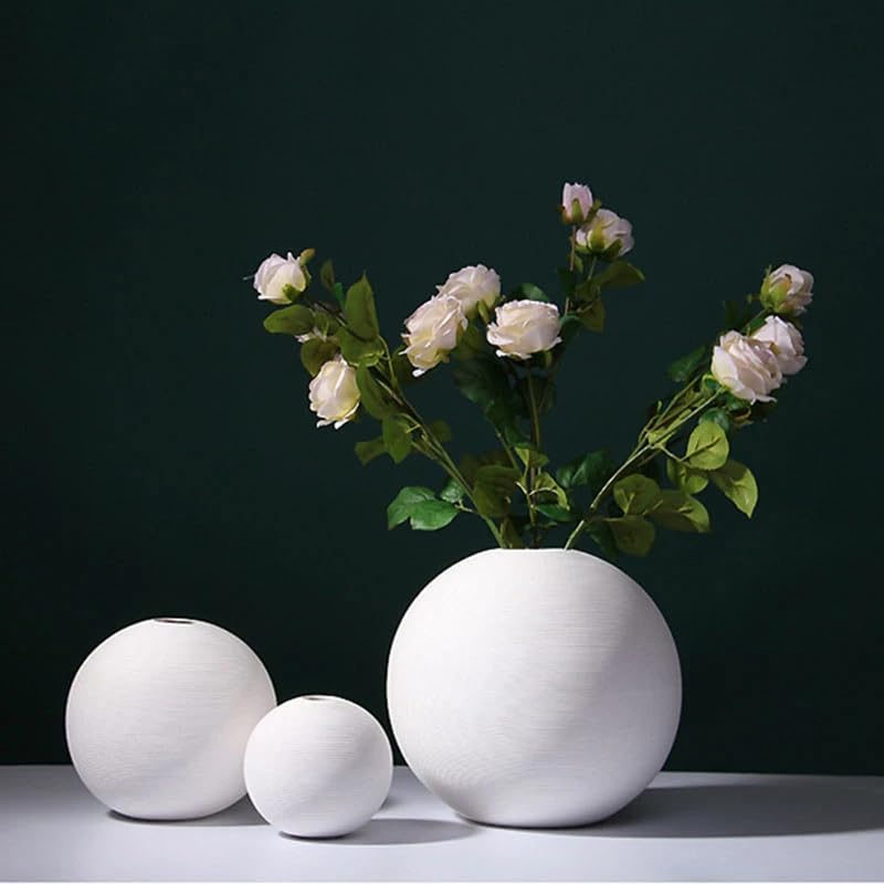 Three white vases filled with beautiful flowers, adding a touch of elegance and color to any space.